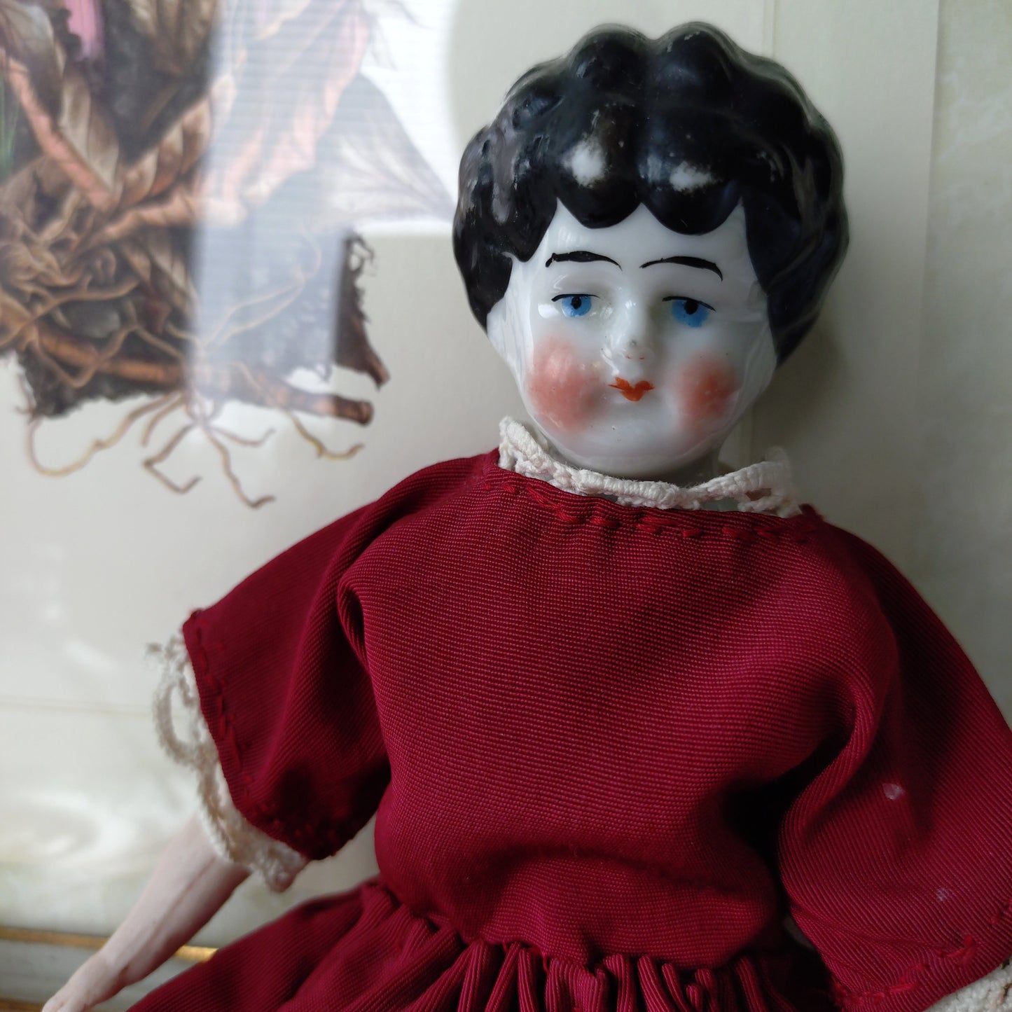 The doll in the red dress is approximately 21 cm high and likely dates to around 1900.