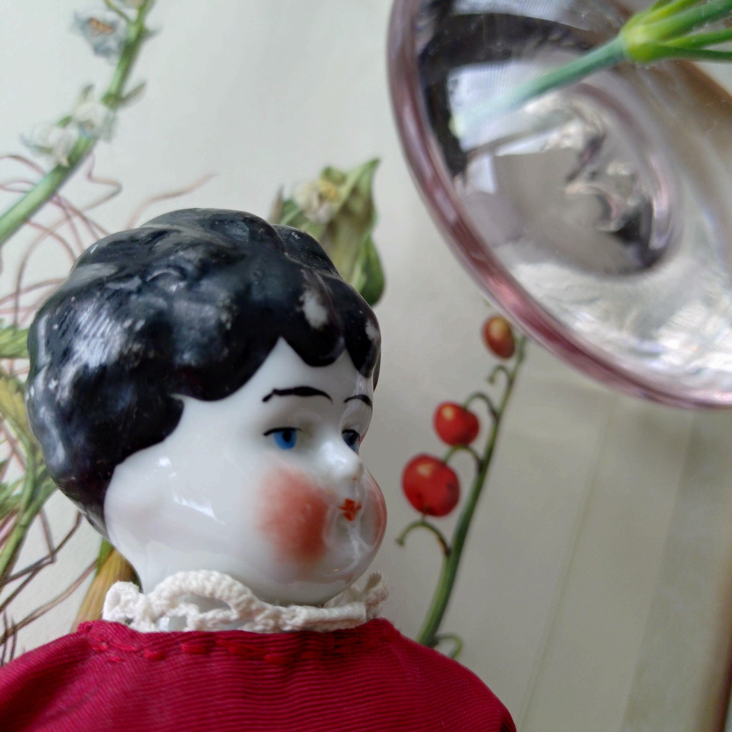 The doll in the red dress is approximately 21 cm high and likely dates to around 1900.
