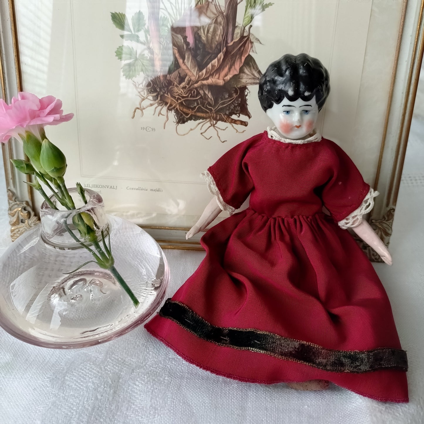The doll in the red dress is approximately 21 cm high and likely dates to around 1900.