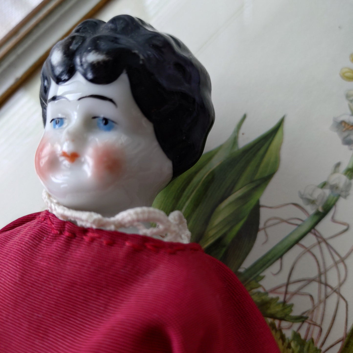 The doll in the red dress is approximately 21 cm high and likely dates to around 1900.