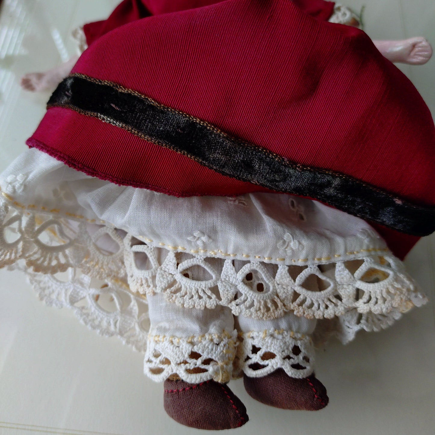 The doll in the red dress is approximately 21 cm high and likely dates to around 1900.