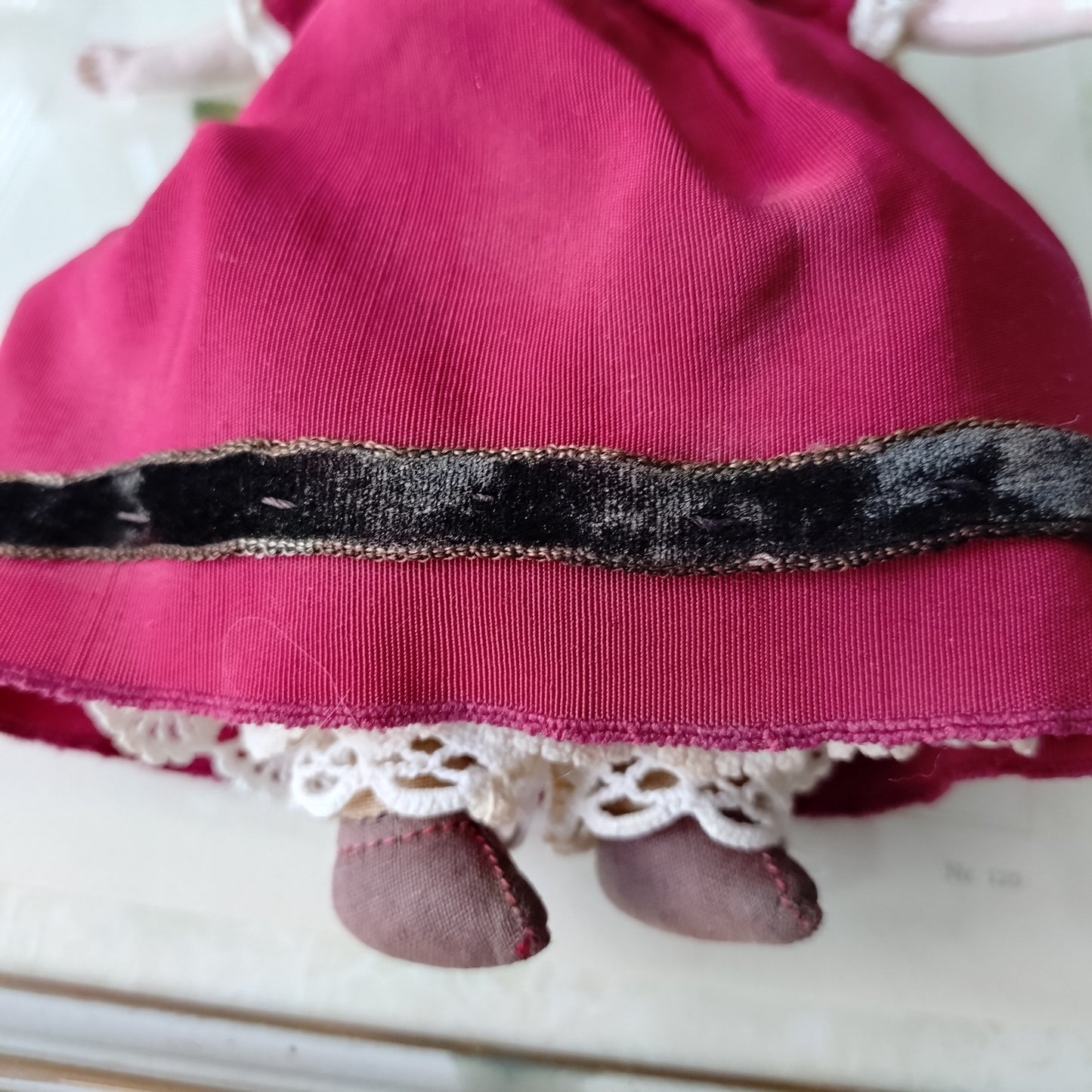 The doll in the red dress is approximately 21 cm high and likely dates to around 1900.