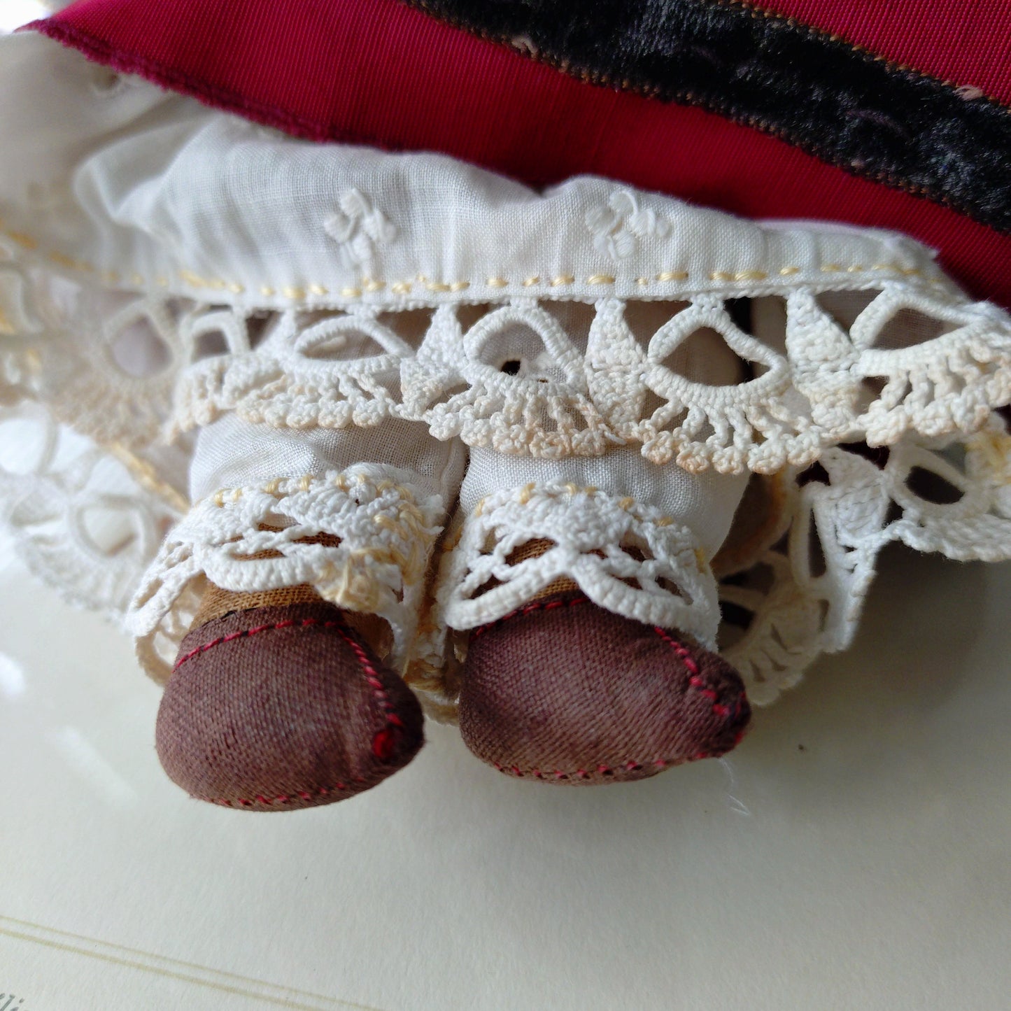 The doll in the red dress is approximately 21 cm high and likely dates to around 1900.