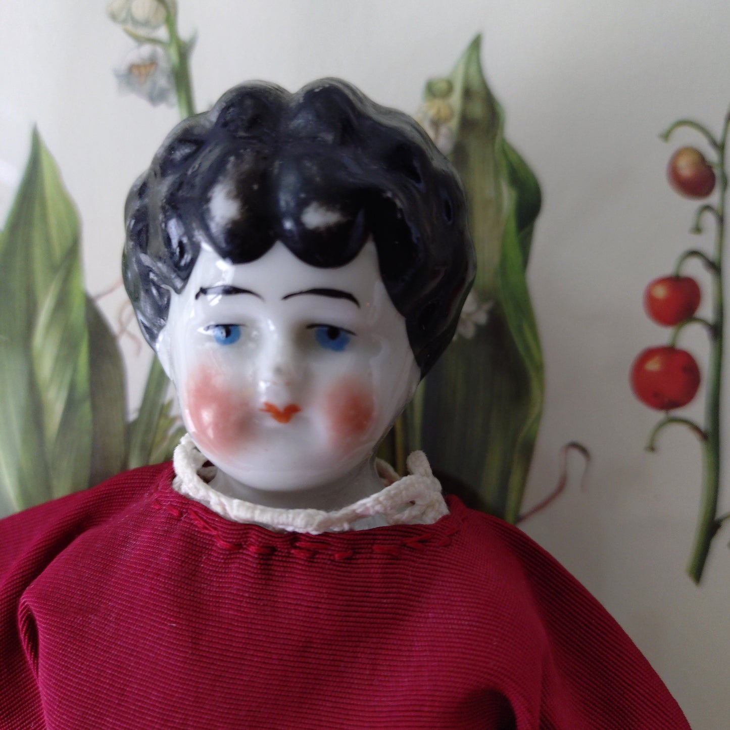 The doll in the red dress is approximately 21 cm high and likely dates to around 1900.