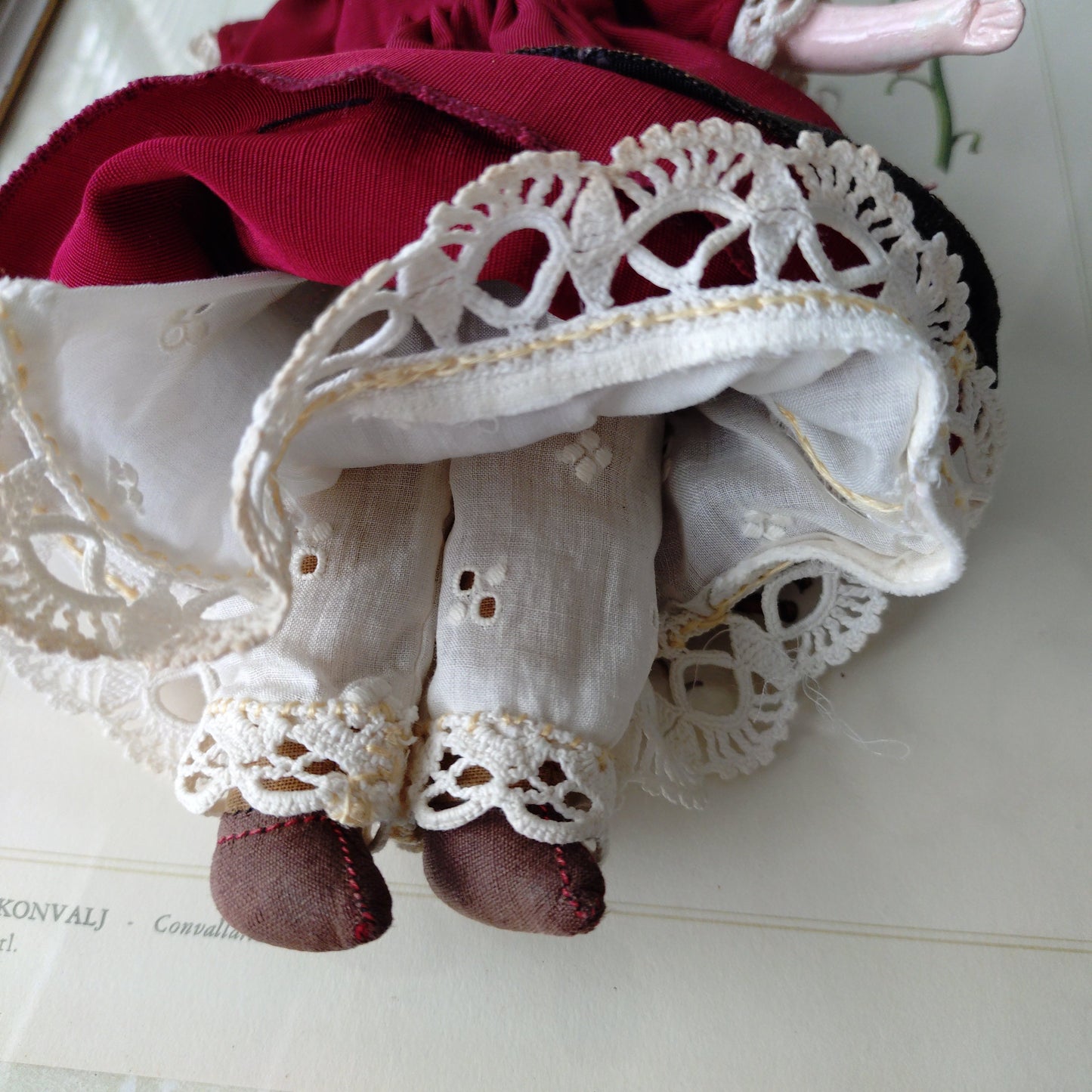 The doll in the red dress is approximately 21 cm high and likely dates to around 1900.